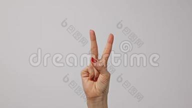 女人举起两个手指，表示和平或胜利的象征或字母V。女人一只手举起两个手指